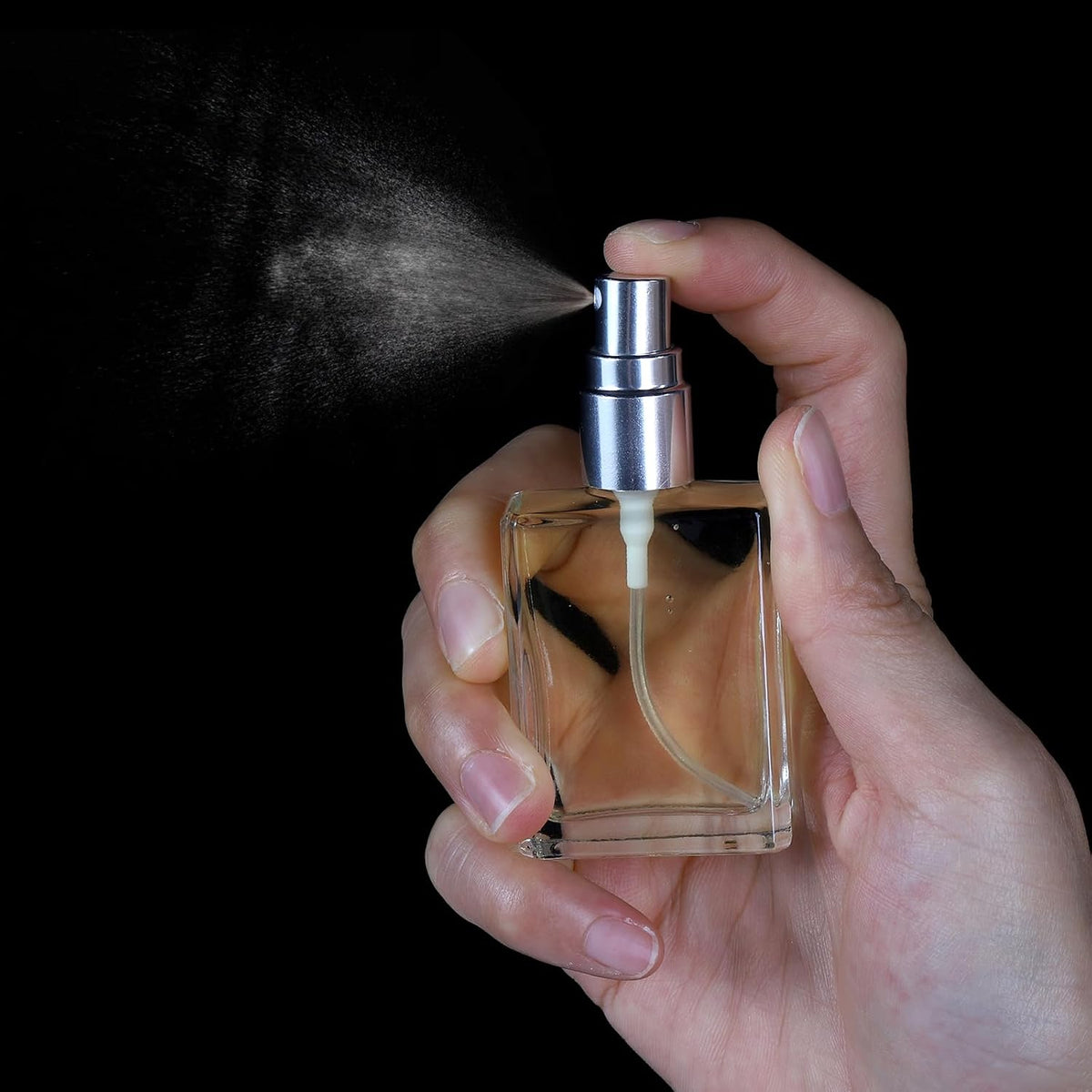 15ml square glass perfume bottle with spray nozzle held by hand against a black background
